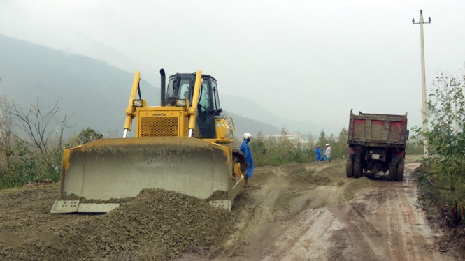 Công nhân, máy móc làm việc trong mưa.